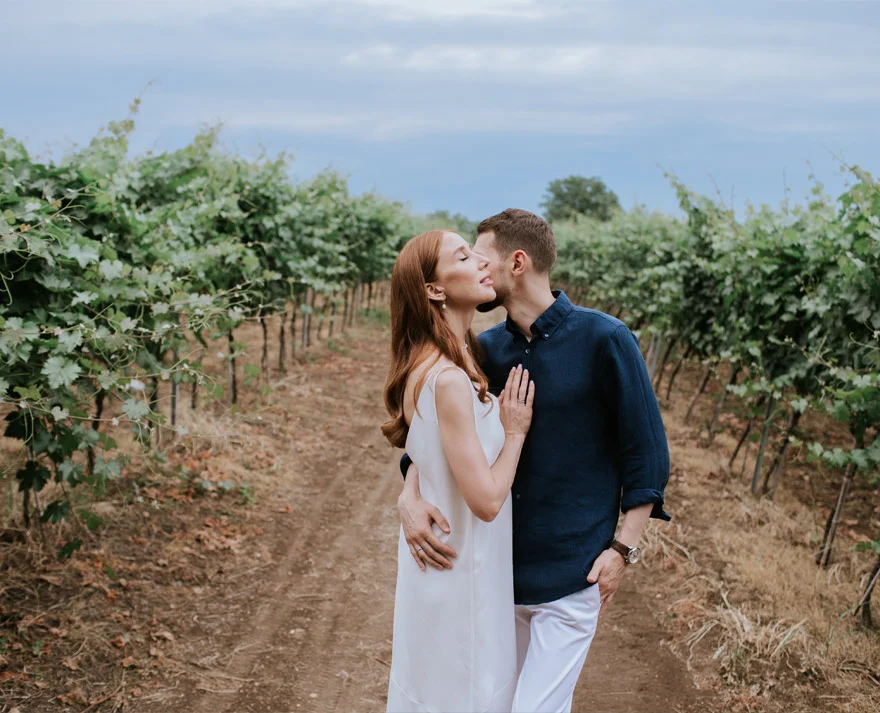 Couple standing amidst green vineyards